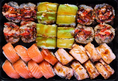 Asya yemeği seti. Sushi, siyah bir arkaplanda yuvarlanıyor. Üst manzara, yukarıda.