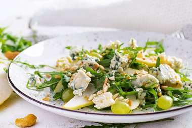 Armut salatası, mavi peynir, üzüm, roka ve hafif arkaplanda baharatlı sos. Sağlıklı beslenme.