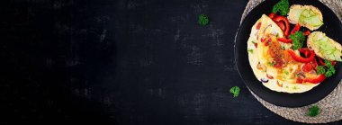 Kahvaltıda. Kırmızı biberli omlet, peynirli ve siyah tabakta sandviçli domates. Frittata - İtalyan omleti. Üst görünüm, afiş, yukarıda