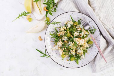 Armut salatası, mavi peynir, üzüm, roka ve hafif arkaplanda baharatlı sos. Sağlıklı beslenme. Üst görünüm, genel görünüm