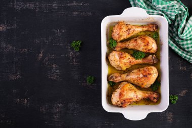 Koyu bir arka planda fırında tavuk budu. Üst manzara, düz uzanma