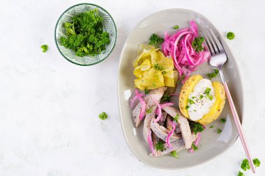 Fırında patates, soğan ve tabakta salatalık turşusu ile ringa balığı. Geleneksel mutfak. Üst görünüm, genel görünüm