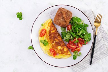 Domatesli omlet, jambon, peynir ve tabakta mısır salatası. Frittata - İtalyan omleti. Üst görünüm, genel görünüm