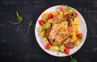 Beyaz tabakta patates ve fırında tavuk. Karanlık arka plan. Üst görünüm, alanı kopyala.