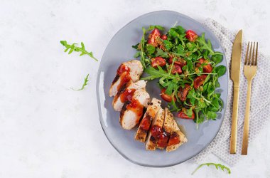 Kızarmış tavuk fileto salata, taze domates ve roka. Üst manzara, düz uzanma