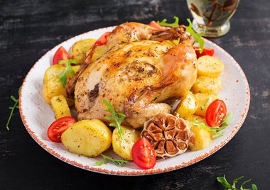 Beyaz tabakta patates ve fırında tavuk. Koyu arkaplan.