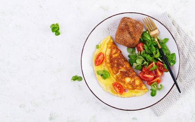 Domatesli omlet, jambon, peynir ve tabakta mısır salatası. Frittata - İtalyan omleti. Üst görünüm, genel görünüm