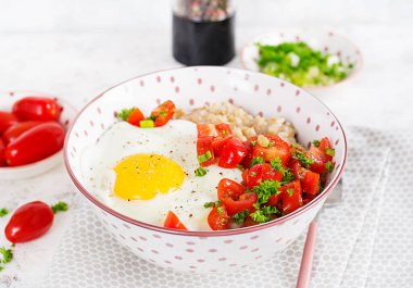 Breakfast oatmeal porridge with roasted egg and tomatoes salad. Healthy balanced food.