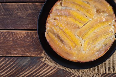 Banana caramel pie or cake on a black plate on a wooden background.Top view, overhead