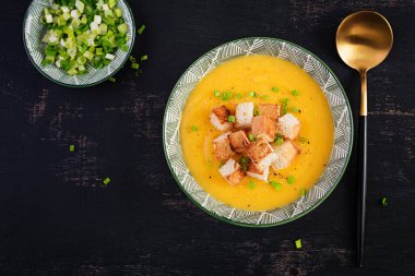 Creamy pumpkin puree soup with croutons, peppers and green onions. Top view, above