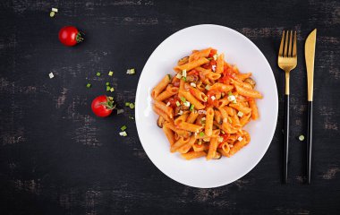 Classic italian pasta penne marinara with mussels and green onions on dark table. Penne pasta with sauce marinara. Top view, overhead