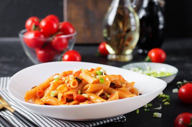 Classic italian pasta penne marinara with mussels and green onions on dark table. Penne pasta with sauce marinara.