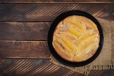 Banana caramel pie or cake on a black plate on a wooden background.Top view, overhead