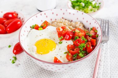 Breakfast oatmeal porridge with roasted egg and tomatoes salad. Healthy balanced food.