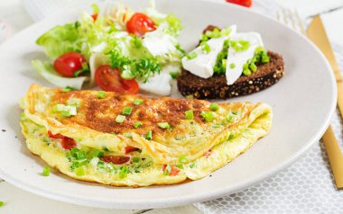 Breakfast. Omelette with tomatoes, cheese, green onions and sandwich with feta cheese.  Frittata - italian omelet.