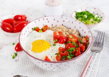 Breakfast oatmeal porridge with roasted egg and tomatoes salad. Healthy balanced food.