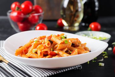 Classic italian pasta penne marinara with mussels and green onions on dark table. Penne pasta with sauce marinara.