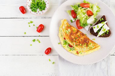 Breakfast. Omelette with tomatoes, cheese, green onions and sandwich with feta cheese.  Frittata - italian omelet. Top view, above