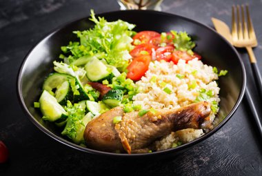 Healthy salad with chicken leg, tomatoes,  cucumber and lettuce  on dark background. Healthy lunch. Dietary menu.
