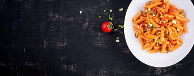 Classic italian pasta penne marinara with mussels and green onions on dark table. Penne pasta with sauce marinara. Top view, banner