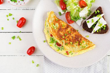 Breakfast. Omelette with tomatoes, cheese, green onions and sandwich with feta cheese.  Frittata - italian omelet. Top view, above