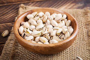 Pistachio nuts in shell  in bowl on wooden background.