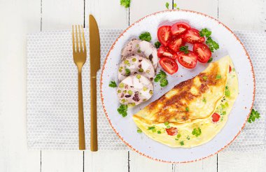 Kahvaltıda. Domatesli omlet, peynir ve etli terrine ya da beyaz tabakta köfte. Frittata - İtalyan omleti. Keto diyeti. Üst görünüm