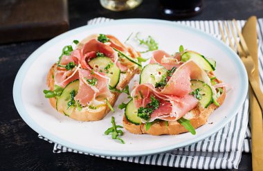 Kahvaltı ya da brunch. Prosciutto ya da jamonlu sandviçi beyaz tabakta aç. Akdeniz mezeleri..