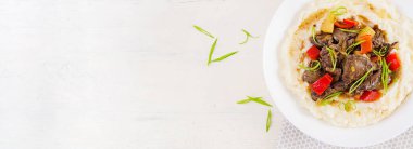 Kızarmış tavuk ciğeri elma, tatlı biber ve patates püresi ile soğan beyaz ahşap masada bir kase. Üst görünüm, afiş