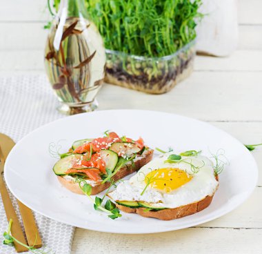 Diyet kahvaltı. Tuzlu somon salatalı sandviç, yeşil salatalık, salatalık, sahanda yumurta ve mikroyeşil.