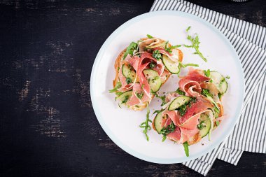 Kahvaltı ya da brunch. Prosciutto ya da jamonlu sandviçi beyaz tabakta aç. Akdeniz aperatifi. Üst görünüm, genel görünüm