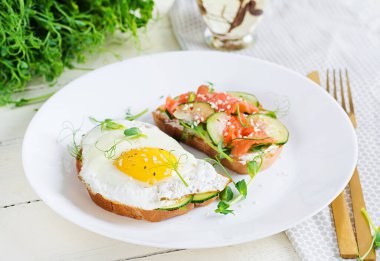 Diyet kahvaltı. Tuzlu somon salatalı sandviç, yeşil salatalık, salatalık, sahanda yumurta ve mikroyeşil.