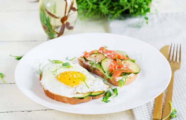 Diyet kahvaltı. Tuzlu somon salatalı sandviç, yeşil salatalık, salatalık, sahanda yumurta ve mikroyeşil.