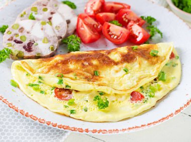 Kahvaltıda. Domatesli omlet, peynir ve etli terrine ya da beyaz tabakta köfte. Frittata - İtalyan omleti. Keto diyeti.