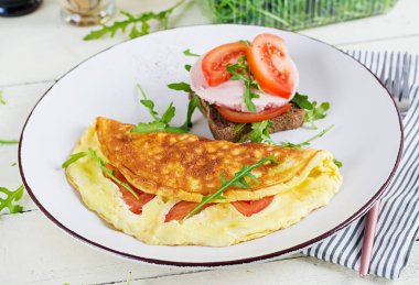 Kahvaltıda. Domatesli omlet, peynirli sandviç ve haşlanmış sosis. Frittata - İtalyan omleti.