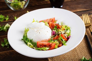 Domatesli salata ve ahşap zemin üzerinde marul ve zeytinyağlı burrata peyniri. İtalyan mutfağı.