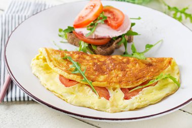 Kahvaltıda. Domatesli omlet, peynirli sandviç ve haşlanmış sosis. Frittata - İtalyan omleti.