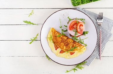 Kahvaltıda. Domatesli omlet, peynirli sandviç ve haşlanmış sosis. Frittata - İtalyan omleti. Üst görünüm, genel görünüm