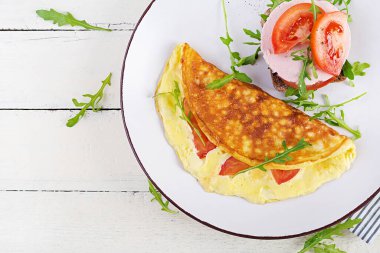 Kahvaltıda. Domatesli omlet, peynirli sandviç ve haşlanmış sosis. Frittata - İtalyan omleti. Üst görünüm, genel görünüm