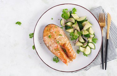 Fırında somon balığı bifteği ve kırmızı soğanlı salatalık. Üst görünüm.