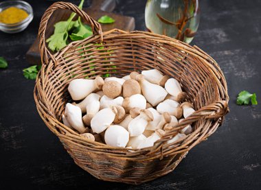 Çiğ kral istiridye mantarı Pleurotus eryngii sepette koyu bir arka planda.