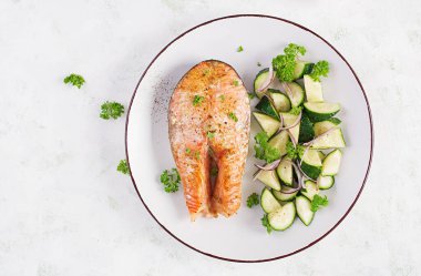 Fırında somon balığı bifteği ve kırmızı soğanlı salatalık. Üst görünüm.