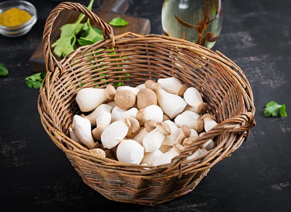 Çiğ kral istiridye mantarı Pleurotus eryngii sepette koyu bir arka planda.