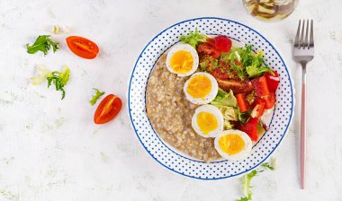 Kahvaltı yulaf lapası haşlanmış yumurta, kiraz domatesleri, tatlı biber ve marul. Sağlıklı dengeli yiyecekler. Üst görünüm, genel görünüm
