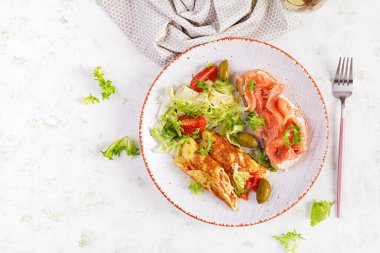 Kahvaltıda. Domatesli omlet ve beyaz tabakta somonlu sandviç. - Öğle yemeği. Üst görünüm