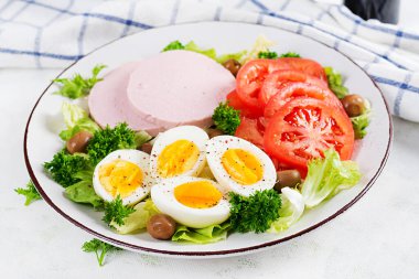 Haşlanmış yumurta, jambon, zeytin, domates ve taze salata. Ketogenik, paleo diyeti. Keto kahvaltısı. Kahvaltı..