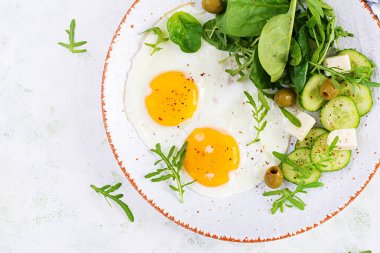 İngiliz kahvaltısı - kızarmış yumurta, peynir, salatalık, zeytin ve ıspanak. Amerikan yemeği. Üst görünüm, genel görünüm