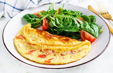 Domatesli omlet ve beyaz tabakta salata. Frittata - İtalyan omleti.