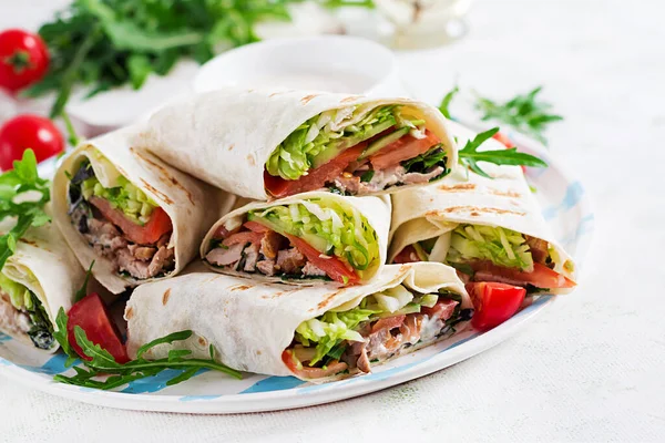 Burritos wraps with beef and vegetables on light  background. Beef tortilla, mexican food.