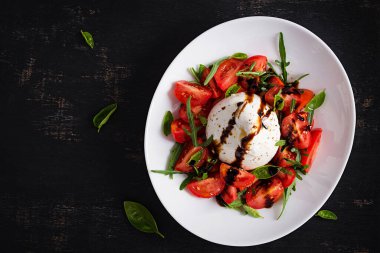 Domatesli salata ve fesleğen ve zeytinyağlı burrata peyniri. İtalyan yemeği. Üst manzara, düz uzanma